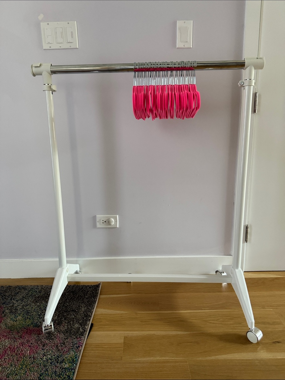 Adjustable White Garment Rack with Bright Pink Hangers